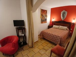 a bedroom with a bed and a chair and a tv at Hotel Rural Hospedería de los Calatravos in La Calzada de Calatrava