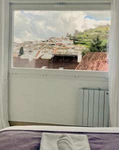 Un dormitorio con una ventana con vista a una ciudad. en Principado de Aracena I, en Aracena