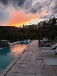 a pool with chairs and a sunset in the background at Membrillar suites de Montaña in Valle Grande