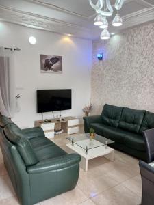 Una sala de estar con un sofá verde y un televisor. en MAG GUEST house, en Abomey-Calavi 9 fotos más