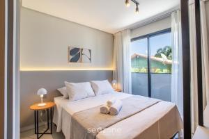 een slaapkamer met een bed en een raam bij Studios Modernos a 2km da Praia do Rosa - RSOs in Praia do Rosa