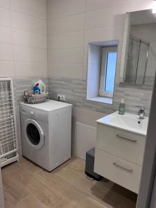 Un baño con lavadora y lavabo. en La p'tite maison, en Courgains