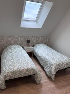 Un dormitorio con dos camas y una ventana. en La p'tite maison, en Courgains