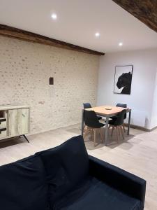 Una sala de estar con un sofá, una mesa y sillas. en La p'tite maison, en Courgains