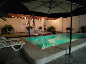 a pool with an umbrella and chairs and a table at Casa de playa Iberico in Caleta Grau