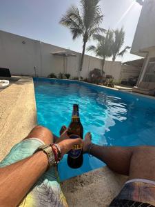 a man holding a bottle of beer by a swimming pool at Casa de playa Iberico in Caleta Grau