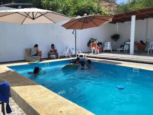 a group of people in a swimming pool with an umbrella at Casa de playa Iberico in Caleta Grau