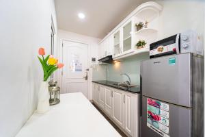 ホーチミン・シティにあるSabina Residence - HCMの白いキャビネットと冷蔵庫のあるキッチン