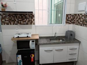 Una pequeña cocina con fregadero y microondas. en Parque Ecológico Studios, en Indaiatuba