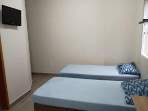 Dos camas en una habitación pequeña con TV. en Parque Ecológico Studios, en Indaiatuba