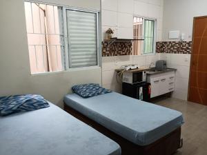 ein kleines Zimmer mit 2 Betten und einer Küche in der Unterkunft Parque Ecológico Studios in Indaiatuba