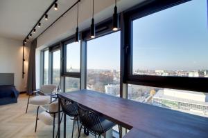 a large room with a table and chairs and large windows at Apartament Loft Olszynki Park in Rzeszów