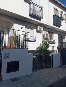 a white building with a gate and balcony at Casa de la Fortuna in Huétor Vega