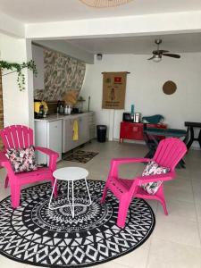 Duas cadeiras cor-de-rosa e uma mesa numa sala de estar em Appartement 2 personnes em Rivière-Salée