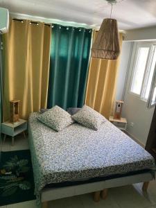 um quarto com cortinas verdes e uma cama com travesseiros em Appartement 2 personnes em Rivière-Salée