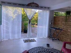 uma sala de estar com cortinas brancas e uma mesa em Appartement 2 personnes em Rivière-Salée mais 4 fotografias