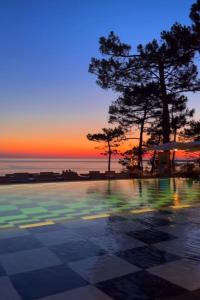 Una puesta de sol sobre una piscina con árboles y el océano. en Villa TILLA 110 m2, terrasse babyfoot fléchettes, en Arcachon