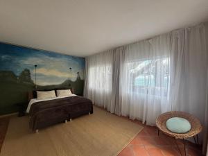 a bedroom with a bed and a large window at Suite Vigia Jardim in Jardim do Mar