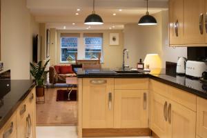 a kitchen with wooden cabinets and black counter tops at Garden flat in Bath