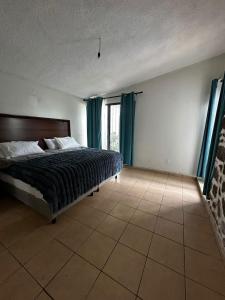 a bedroom with a bed and a window with blue curtains at Casa en Cuernavaca Morelos in Cuernavaca