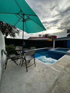 een tafel en stoelen met een parasol naast een zwembad bij Casa en Cuernavaca Morelos in Cuernavaca