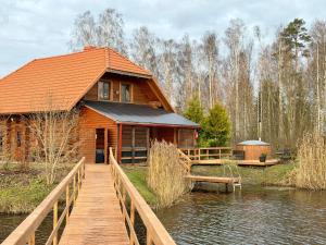 a log cabin with a bridge over the water at Kundziņu salas in Vidriži