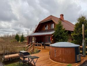 a house with a hot tub on a wooden deck at Kundziņu salas in Vidriži