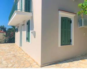 a building with green shutters and a balcony at Vero's Seaview Studio in Lefki