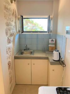 una piccola cucina con un lavandino e una finestra di Vero's Seaview Studio a Lefki