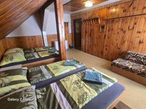 two beds and a couch in a room with wooden walls at Horská CHATA U ŠPIČÁKU in Josefuv dul +21 photos