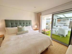 a bedroom with a large white bed and a balcony at Kana Vista in Plettenberg Bay