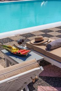 Sandy's Paradise في بيريسا: وعاء من الخضراوات وقبعة على طاولة بجوار حمام سباحة