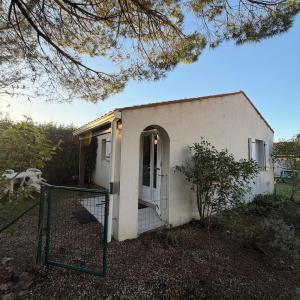 una pequeña casa blanca con una puerta delante en Maison de vacances 3 étoiles - Sous les Pins, en Ozillac