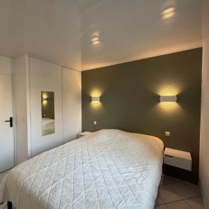 Un dormitorio con una cama y dos luces en la pared. en Maison de vacances 3 étoiles - Sous les Pins, en Ozillac