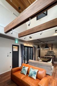 a living room with an orange couch and a kitchen at Casa Stay Kokura 1 - Vacation STAY 18791v in Kitakyushu