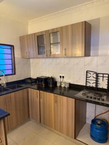 a kitchen with wooden cabinets and a black counter top at Wrens cosy home in Diani Beach