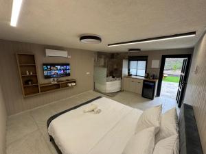 a bedroom with a large white bed and a television at רויאל דליה in Dāliyat el Karmil