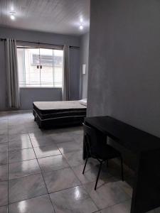 een slaapkamer met een bed, een bureau en een raam bij KITNET ELVIS PRESLEY - Largo do Machado in Rio de Janeiro +11 foto's