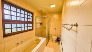 een badkamer met een bad, een toilet en een raam bij Estalagem Entardecer da Serra in Monte Verde +82 foto's