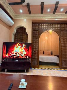 een woonkamer met een grote tv en een bed bij Appartement pour les séjours in Marrakesh