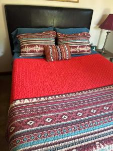 un letto con una coperta rossa e dei cuscini sopra di The Barn House a Eureka Springs