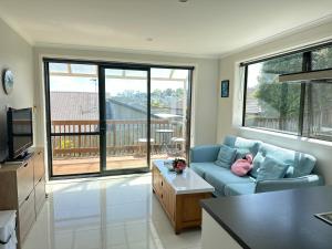 a living room with a blue couch and a balcony at Albany Sunny Deck Retreat in Auckland