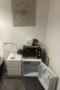 Una pequeña cocina con encimera y microondas. en fAiRy DeLL - 247 check in Boutique hotel with cozy lockable rooms, tv, tea tray with choccies, free wifi and parking, COA, all are welcome, en Bradford