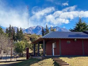 ein kleines rotes Gebäude mit Bergen im Hintergrund in der Unterkunft Cabañas Las Carditas in Mendoza + 4 Fotos