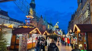 a crowd of people walking down a street with christmas stalls at VULTOR Apartments in Wrocław