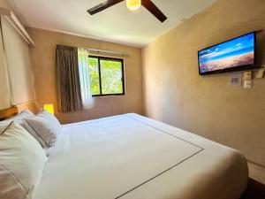 a bedroom with a large bed with a tv on the wall at Albra Tulum in Tulum +112 photos