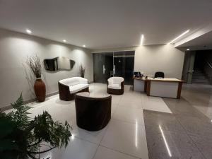 a lobby with two chairs and a tv on a wall at Varandão com vista na Praia dos Namorados in Guarapari