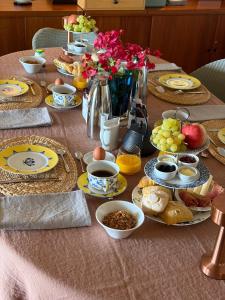 a table with plates of food and fruit on it at Quinta das Eirinhas-Jardim de Bonsai in Tavira