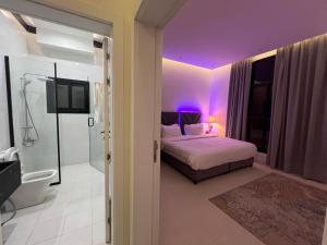 ein Schlafzimmer mit einem Bett und ein Badezimmer mit lila Beleuchtung in der Unterkunft شقة خاصة in Dschidda