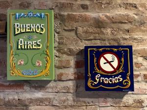 a brick wall with two signs on it at Loft con patio frente a Mercado San Telmo, 2 baños in Buenos Aires